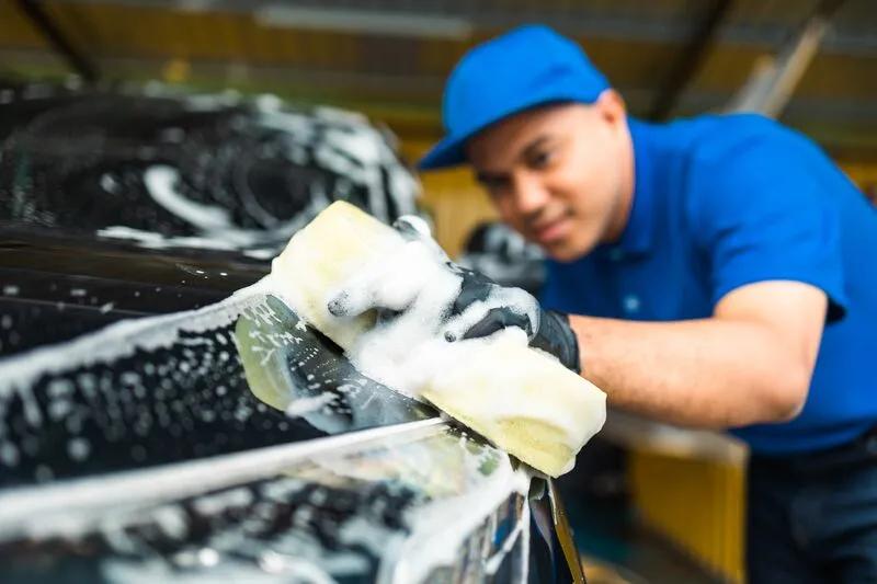 Car wash employee washing car with sponge at Downtowner Car Wash